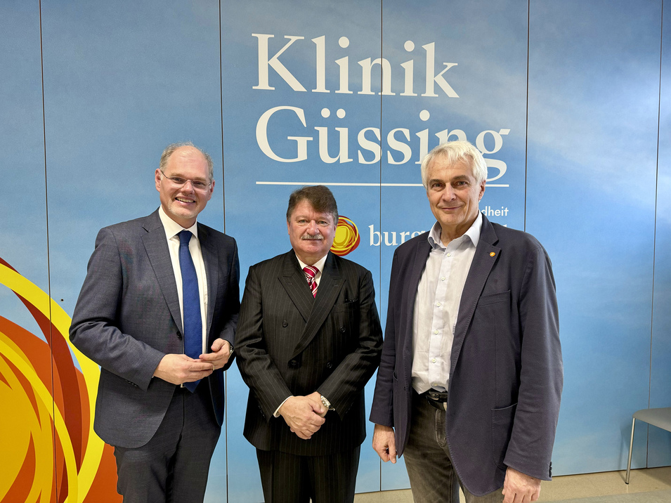 Mag. Franz Öller, Primar Dr. Gerhard Puhr, Univ.-Prof. Dr. Stephan Kriwanek stehen vor dem Logo der Klinik Güssing
