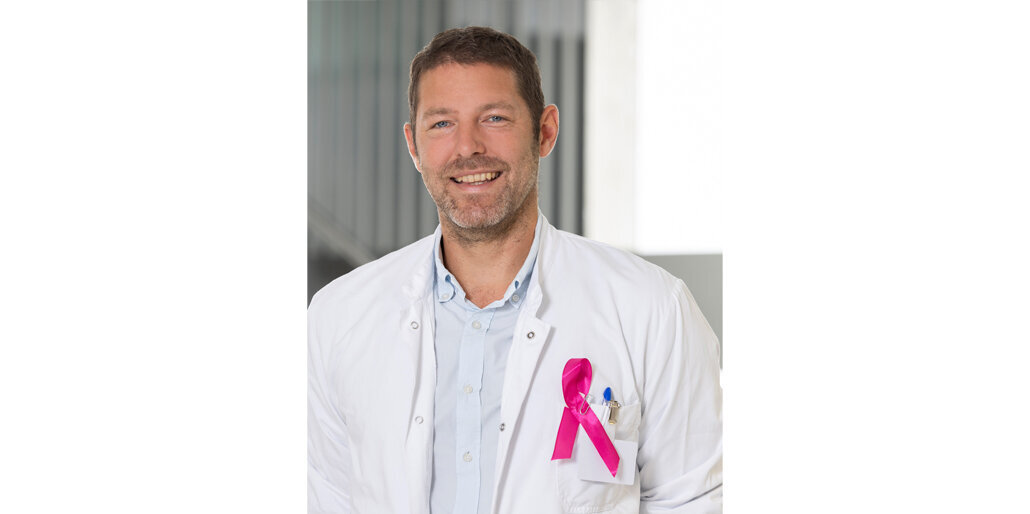 Foto: Gesundheit Burgenland/Muik Dr. Uranitsch im weißen Arztkittel mit dem Brustkrebszeichen in rosa