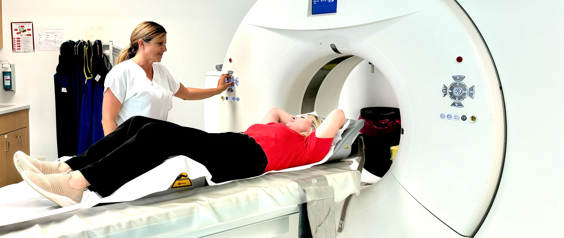 Eine Frau liegt in einem MR-Gerät, daneben steht eine medizinische Fachkraft