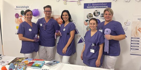 Sechs Personen in Krankenhauskleidung bei einem Infostand