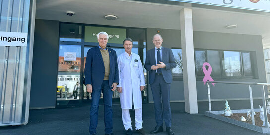 Drei Männer stehen vor dem Eingang der Klinik Güssing