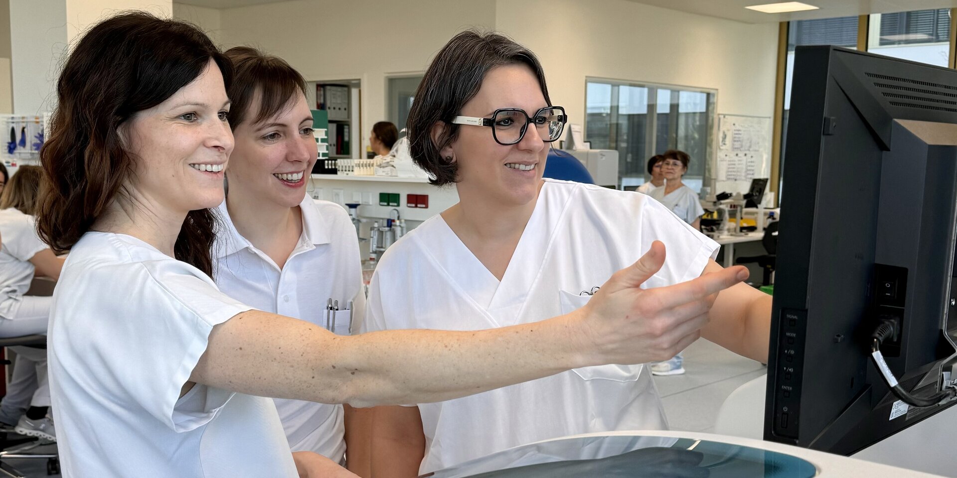 Foto: Gesundheit Burgenland Drei Frauen stehen in einem Labor und schauen auf einen Bildschirm