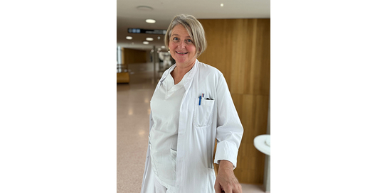 Eine Frau in weißem Arztkittel steht in einer Klinikumgebung