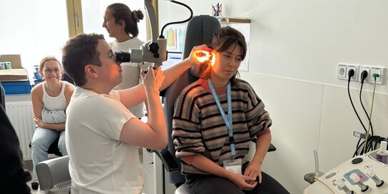 Arzt zeigt im Rahmen der Summer School eine Untersuchung am Ohr