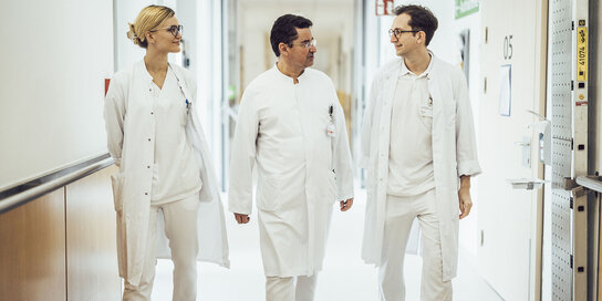 Drei Ärzte gehen durch den Gang eines Spitals