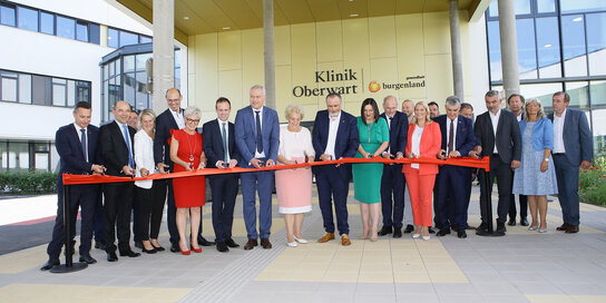 Eine Gruppe Menschen schneidet vor der Klinik Oberwart ein rotes Band durch