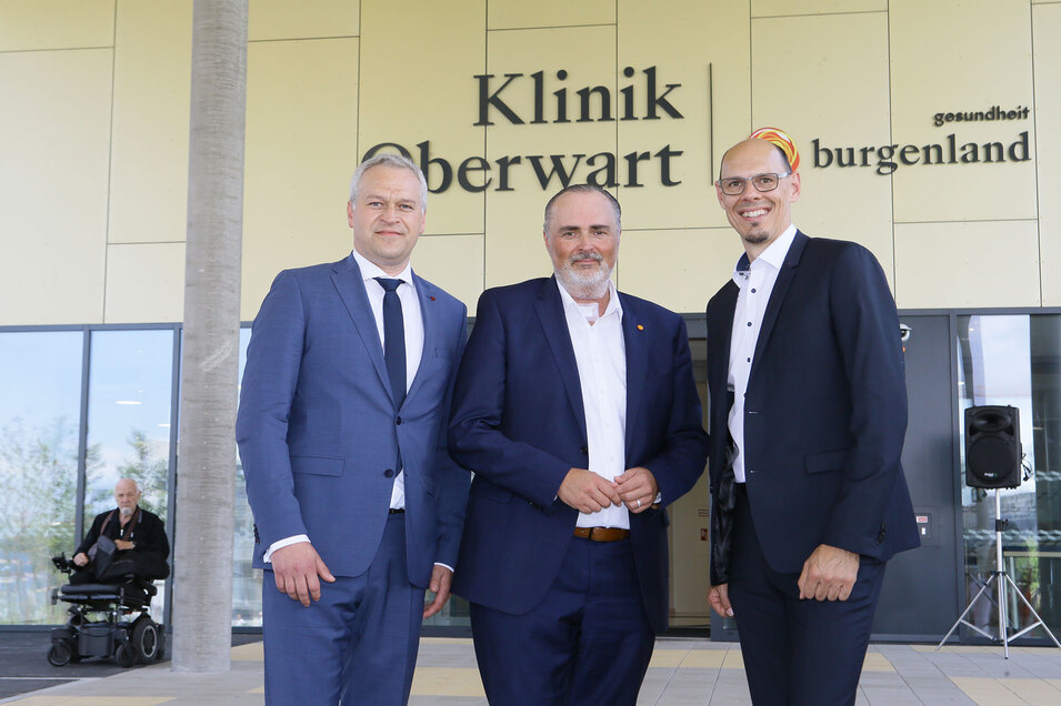 Gruppenfoto: HLH mit den beiden Bauteam-Leitern (Mag. (FH) DI Josef Strohmaier und Baumeister Ing. Christian Hofstädter) vor dem Haupteingang der Klinik Oberwart