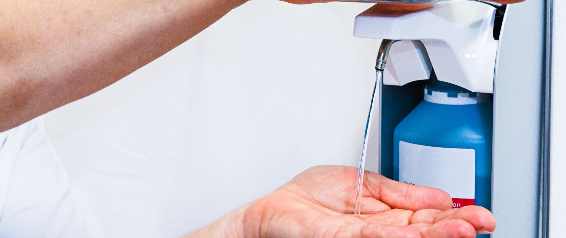 Hände, die einen Hygieneflüssigkeitsspender bedienen