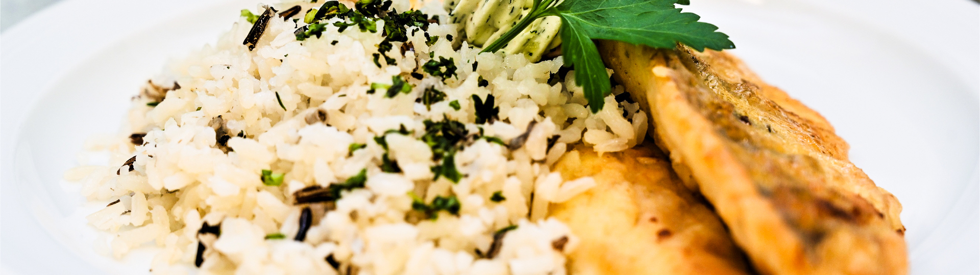 Flacher Teller mit weißem Reis und zwei Stück Naturschnitzel (gesundes Essen)