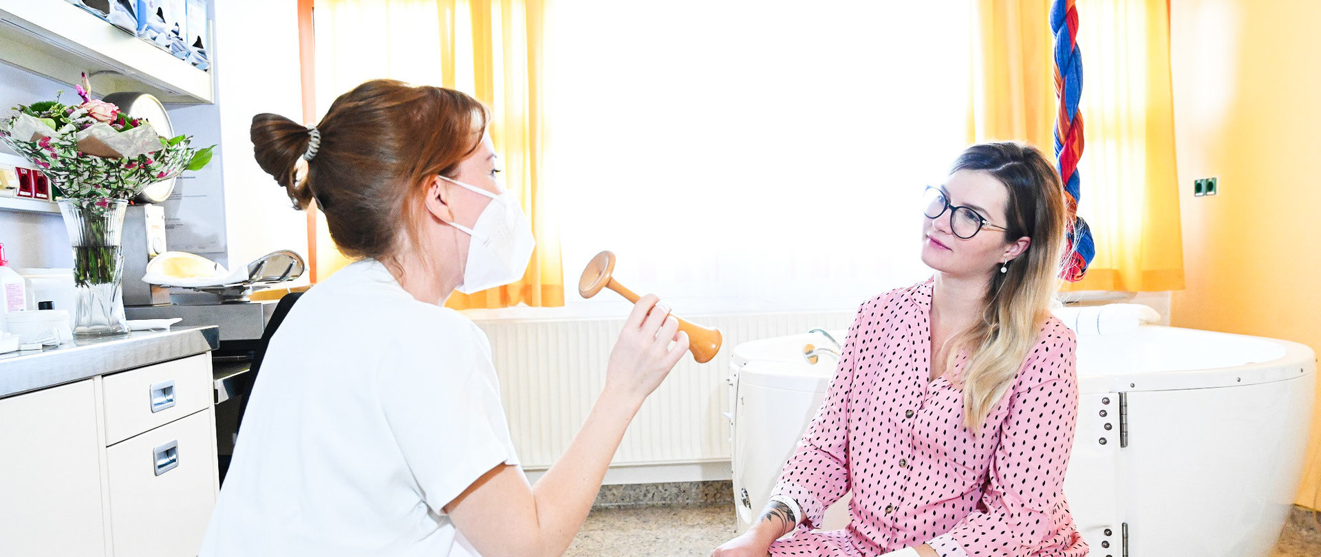 Ärztin mit Stethoskop beim Gespräch mit junger werdenden Mutter